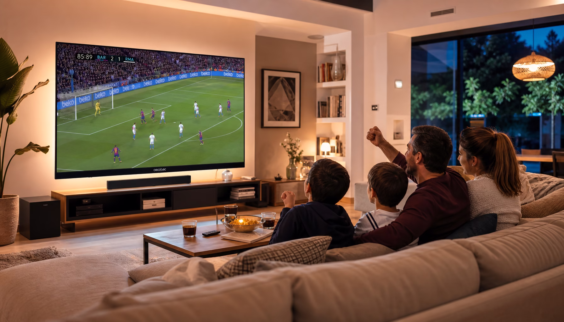 Televisor Cecotec de grandes pulgadas en salón español con familia viendo fútbol